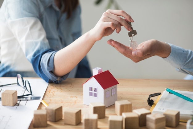 Hand giving house keys across a wooden table
