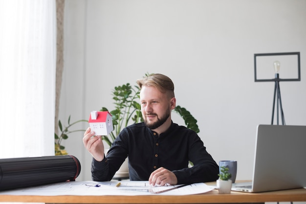 Self-employed professional holding a house model in an office