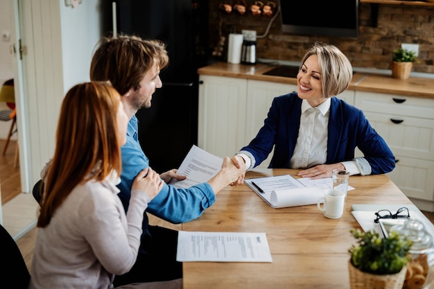 Insurance agent shaking hands with a young couple after a successful meeting